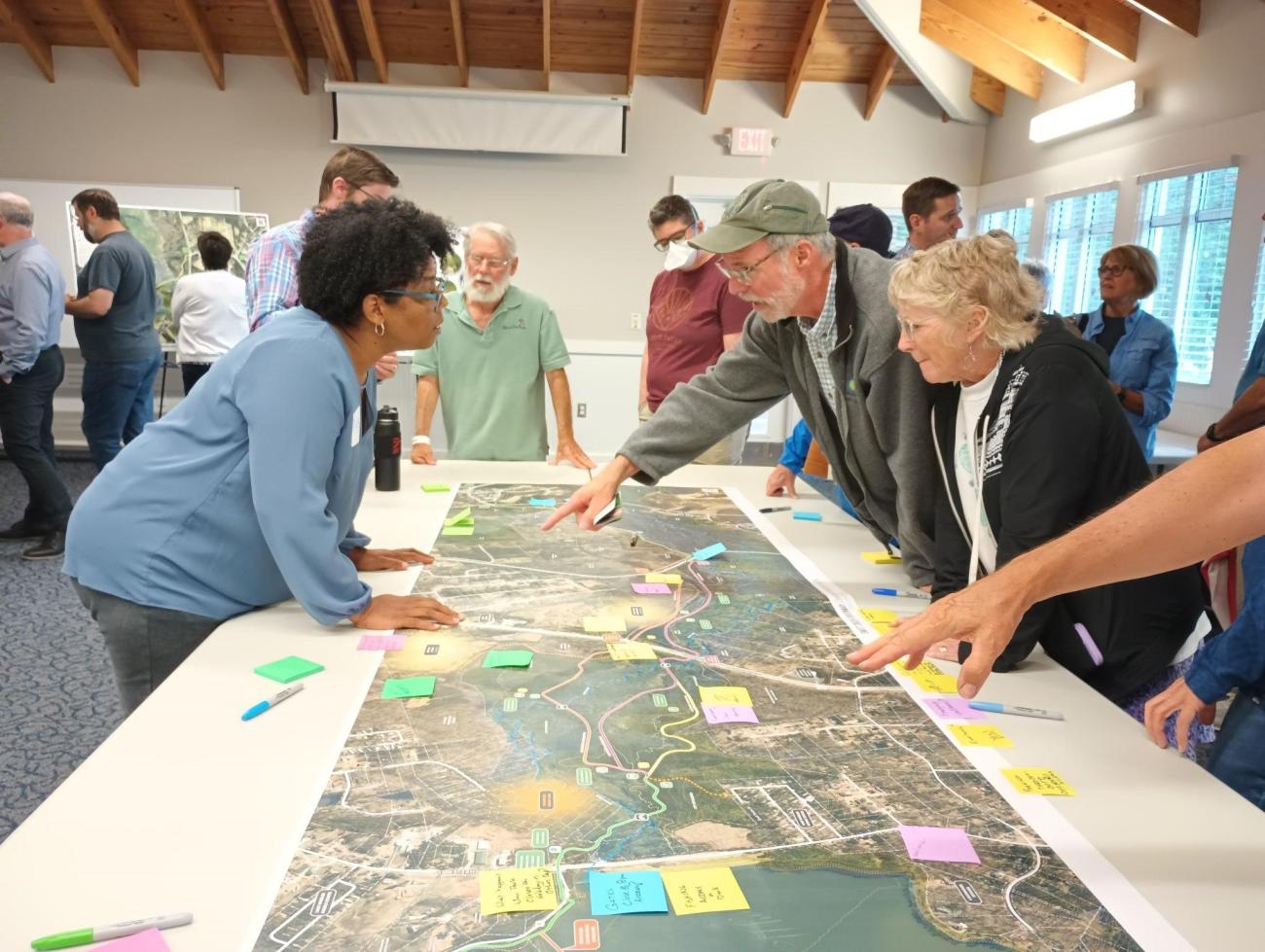 Photo of people looking at and pointing at a map of the proposed Swift Creek Greenway project