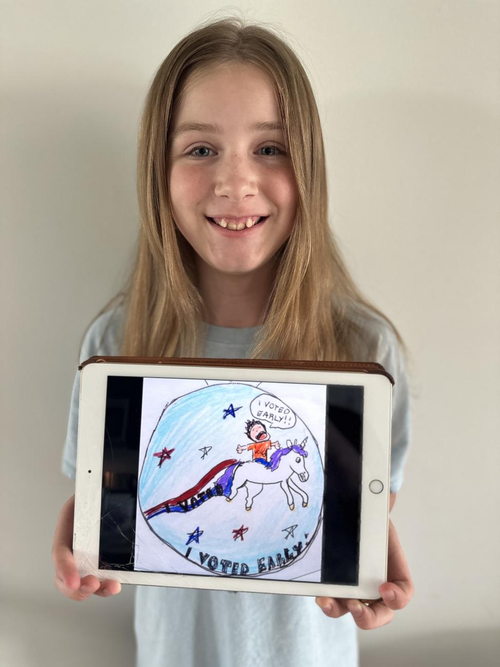 Young girl holding he original voting sticker design featuring a unicorn