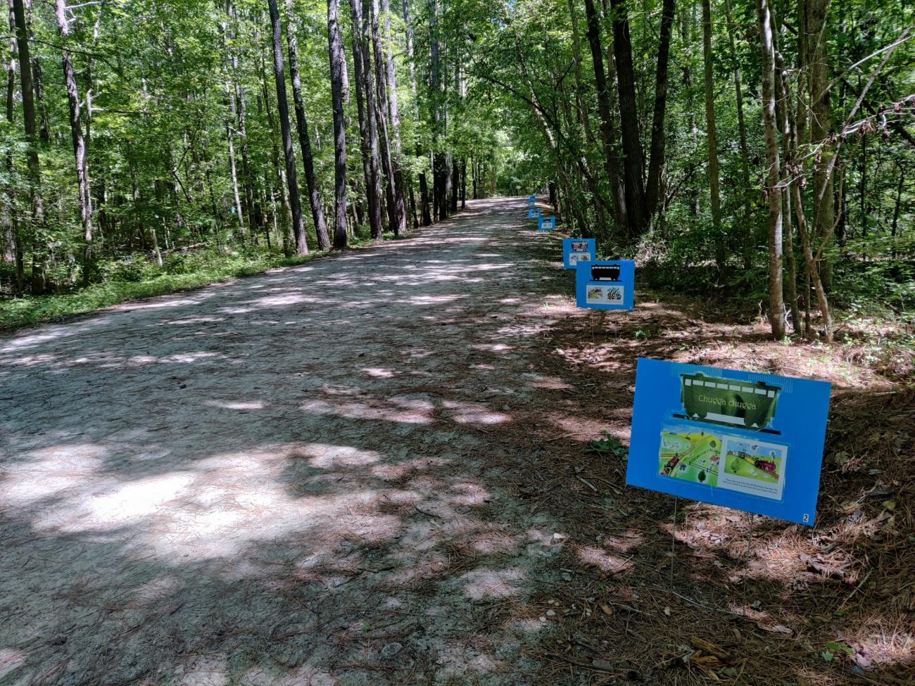 Photo of StoryWalk boards with laminated photos of a book attached to them at the American Tobacco Trail