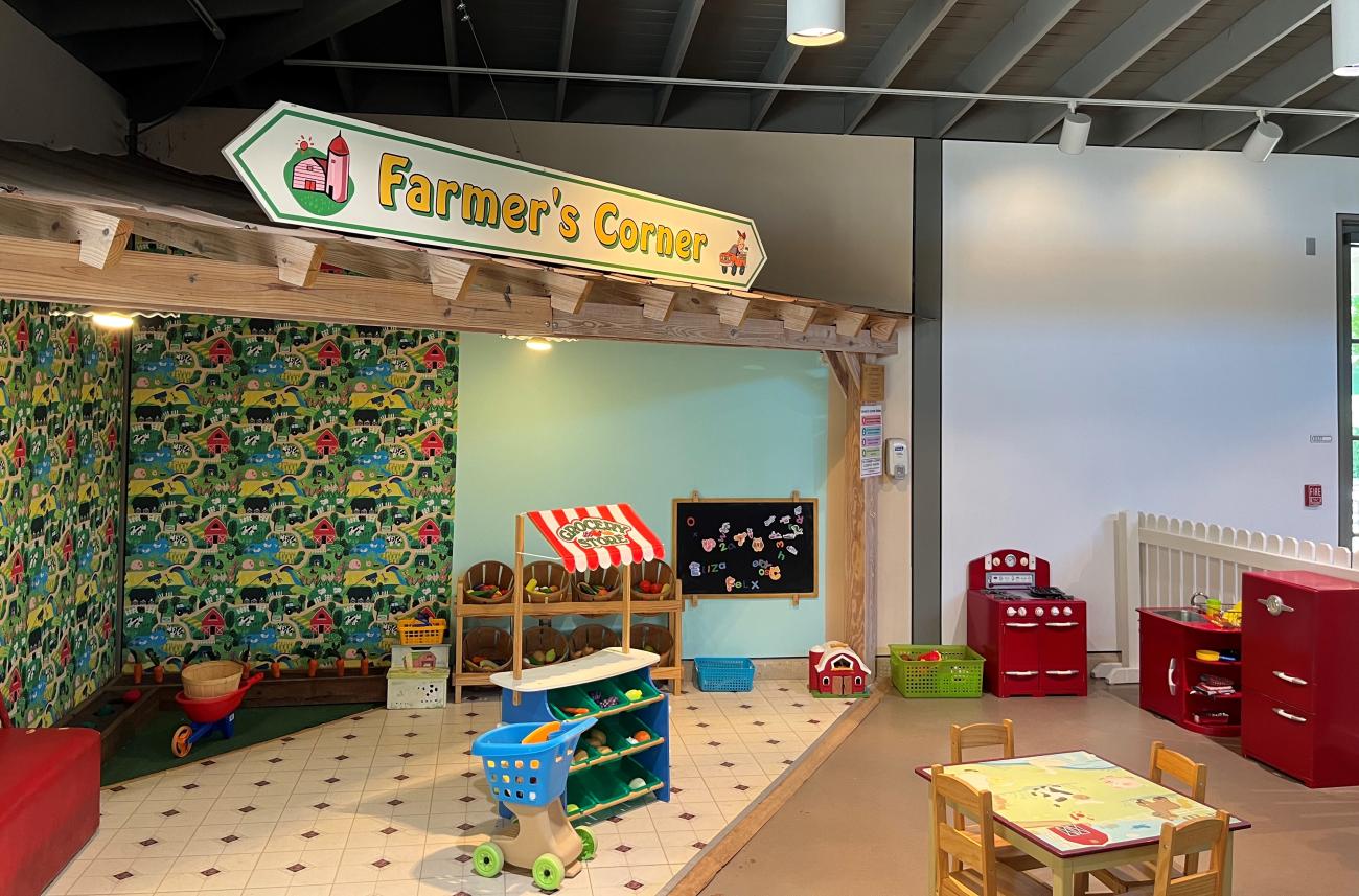 The Farmer's Corner child play area at Historic Oak View County Park with grocery store stand, gardening, table, and kitchen play areas.