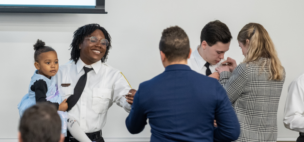 Smiling Academy Student holding a child and Receiving a Pin