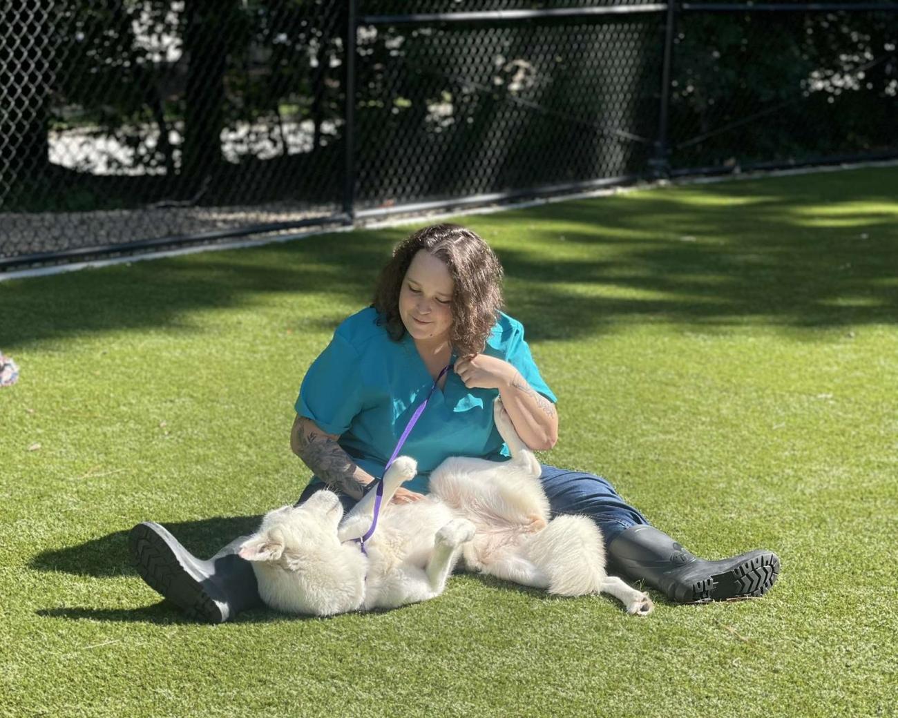 Emily Parker sits in yard at Animal Center, playing with a dog