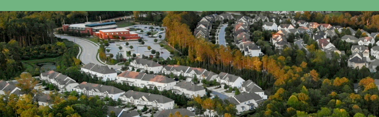 Arial image of suburban neighborhood with trees, homes and roads.