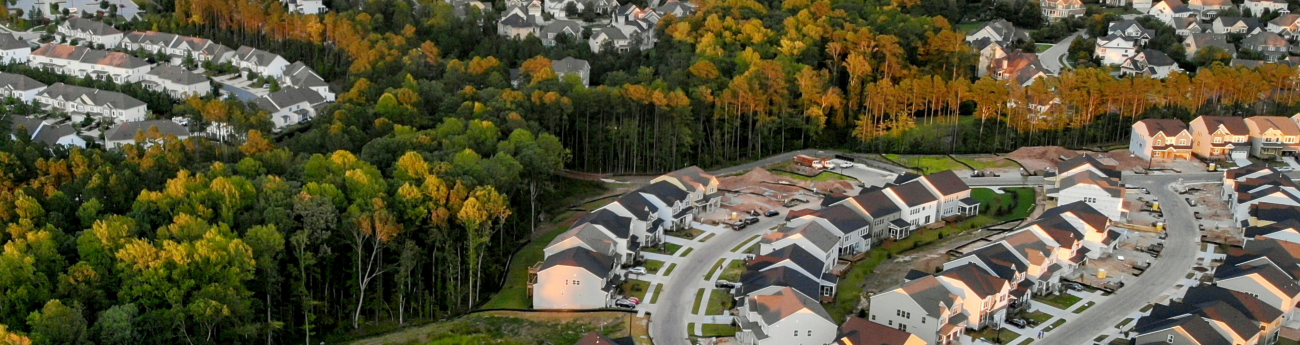 Arial image of suburban neighborhood with trees, homes and roads.