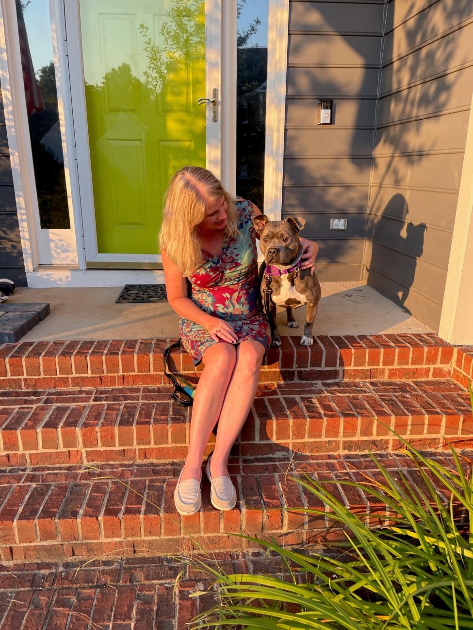 Dr. Caroline Loop sits on the steps with Rhubarb the dog