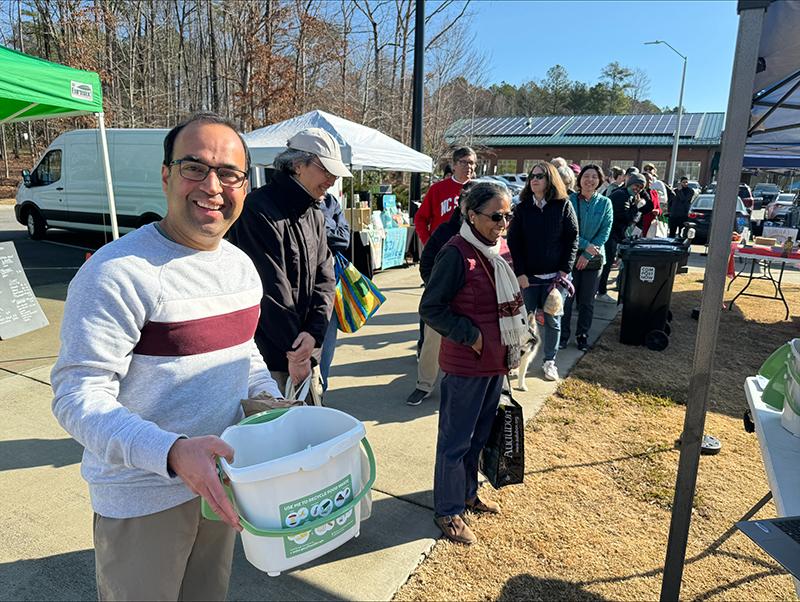 smiling man holds a food recycling bin