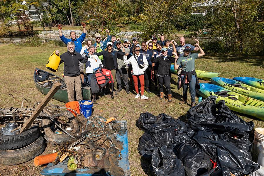 Big Sweep volunteers celebrate behind piles of garbage collected at Crabtree Creek