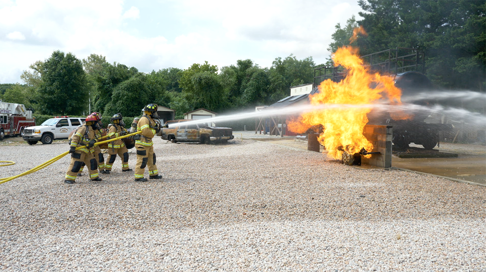 Firefighters holding a hose douse a fire