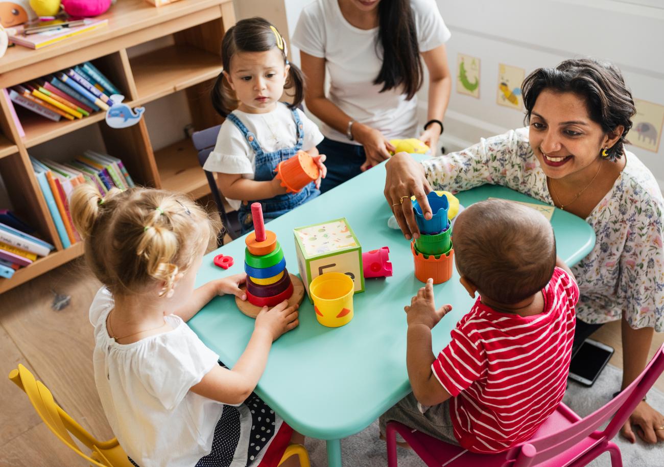 preschool children and teachers play with shapes at a table