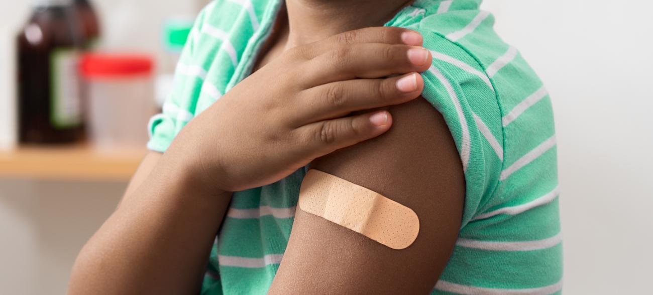 Child with bandage on arm, medical shoulder injection dose and immunization bandage.