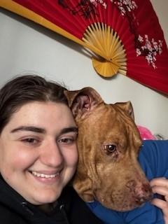 girl smiles with dog over her shoulder