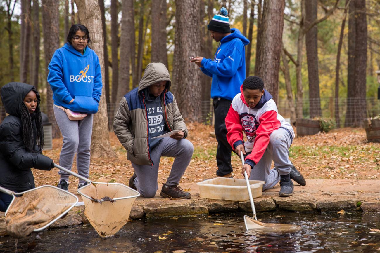 Four youth dipping nets into the educational pond at Blue Jay Point County Park