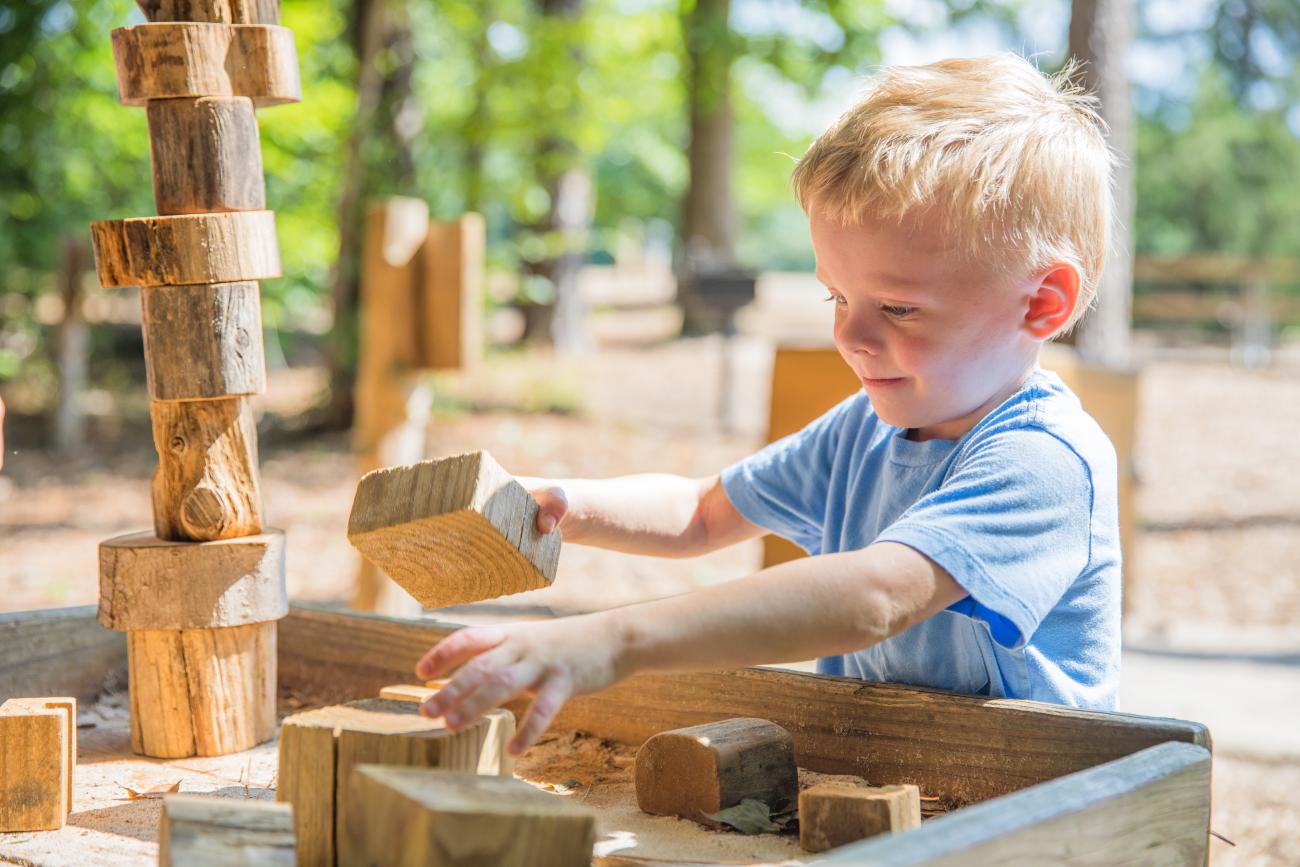 child plays with wood blocks on a table
