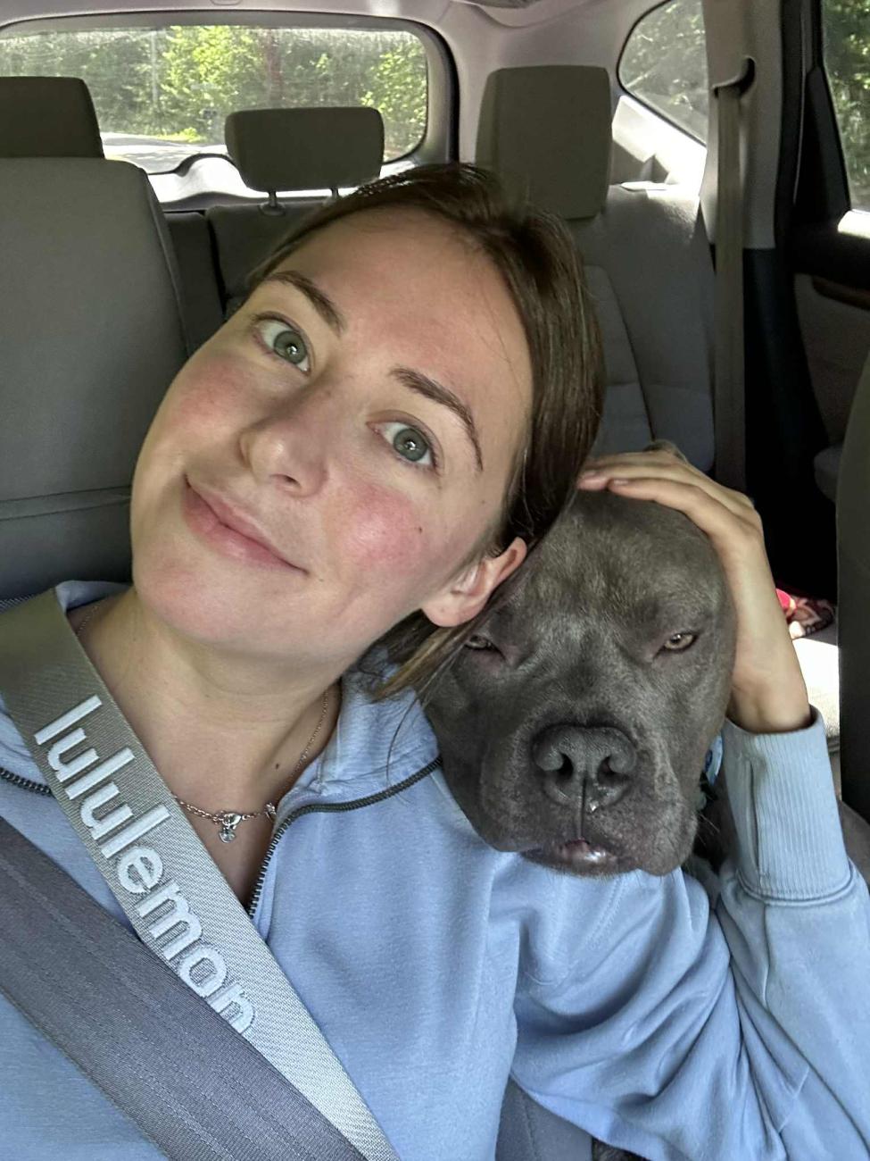 smiling woman rests dog's head on her shoulder