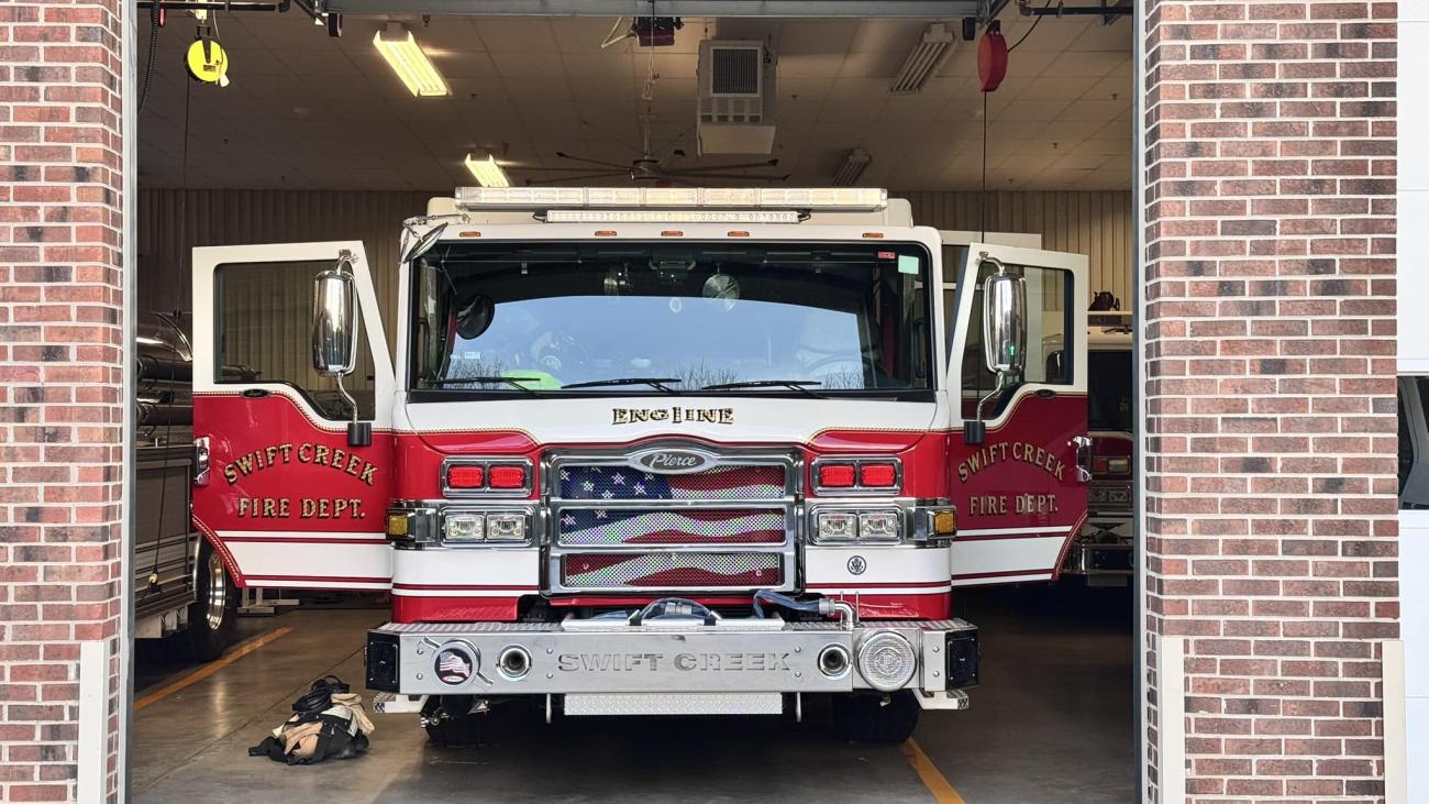 fire truck with doors open sits in the bay of a fire station