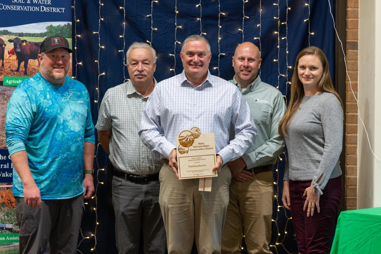 group of five people stands with award