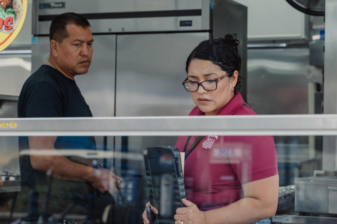 inspector looks at food holding area while restaurant worker looks on