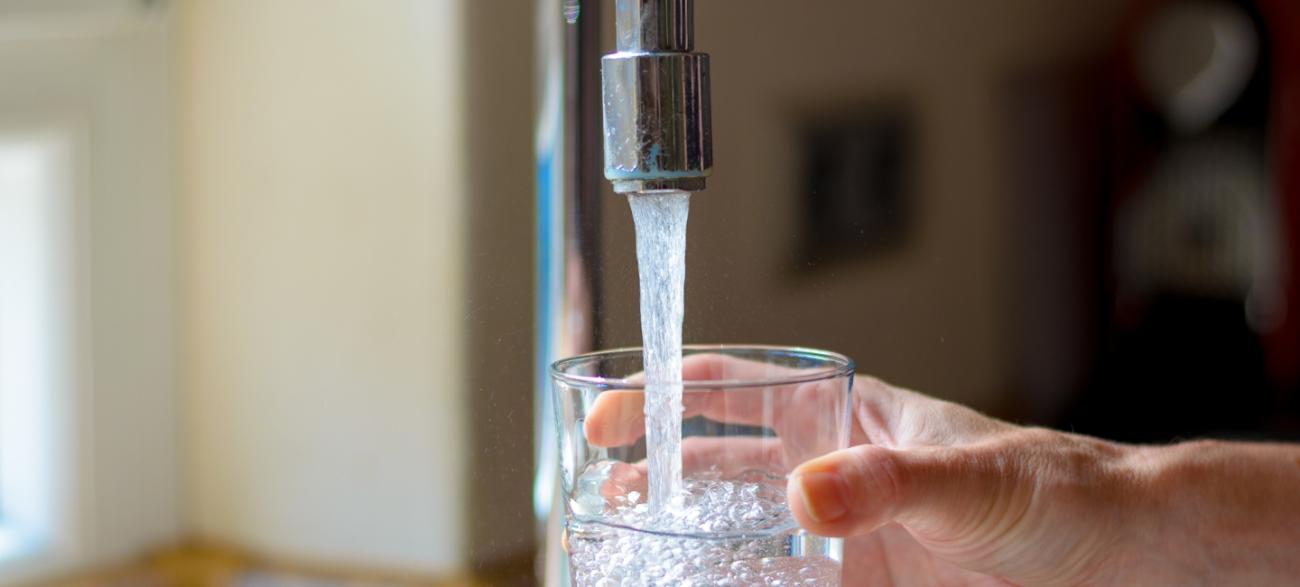 hand holding a glass of water under a running faucet
