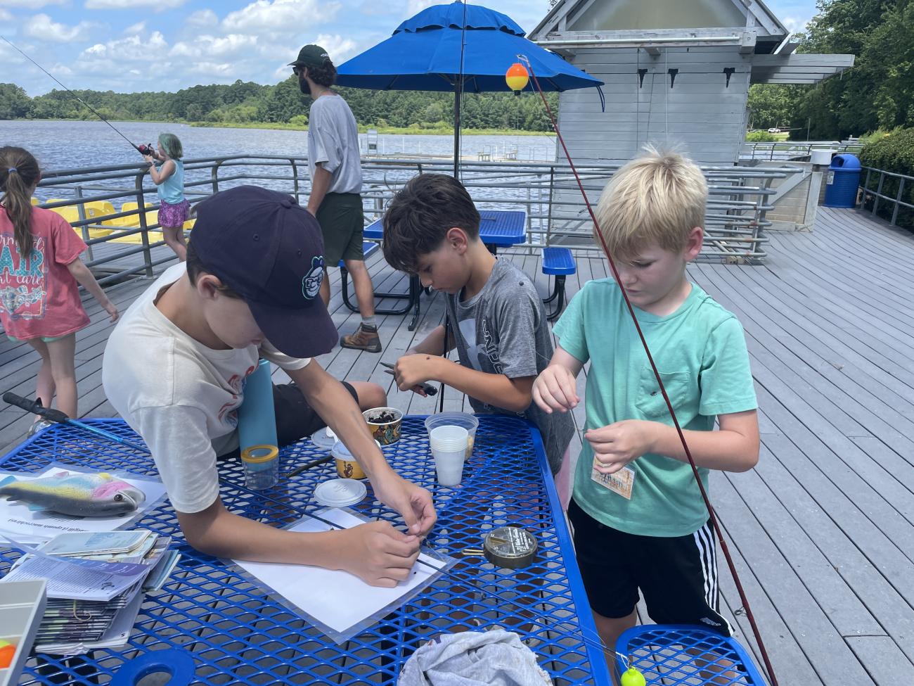 students gathered around table baiting hooks of fishing rods