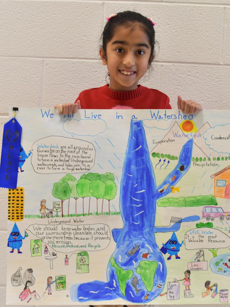 smiling child holds watershed poster