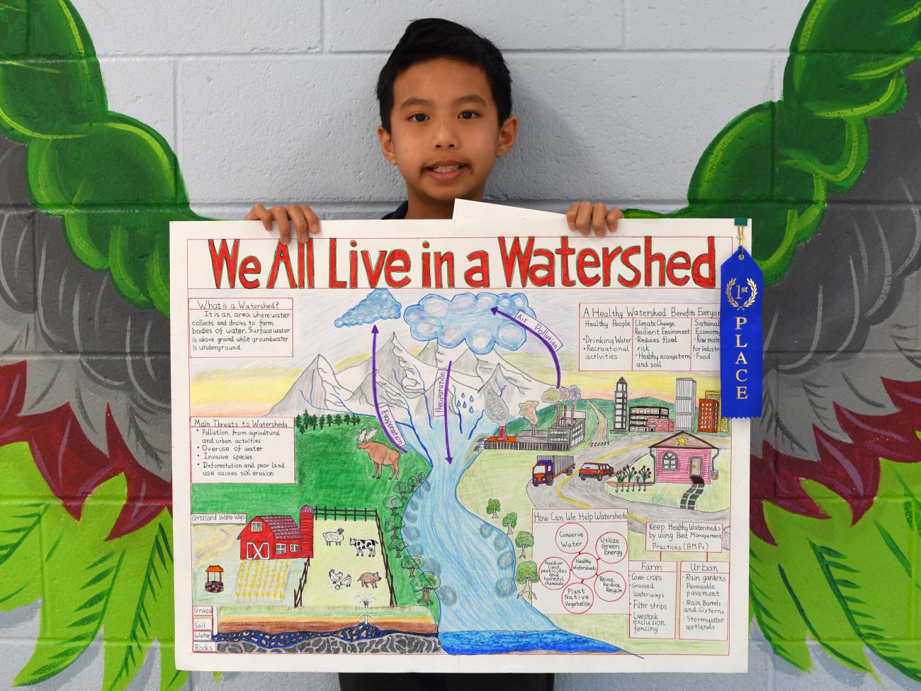 smiling child holds watershed poster