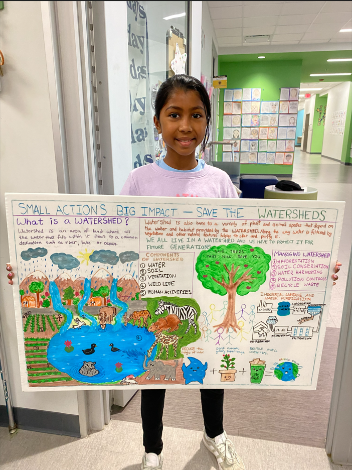 smiling child holds watershed poster