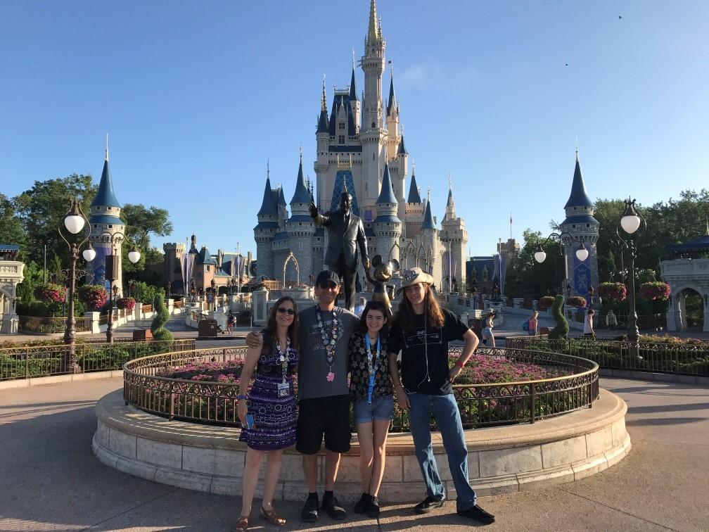 Family posing in front of a castle at a theme park.