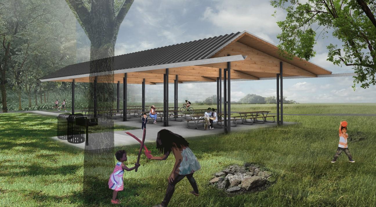 Open-air pavilion with a slanted roof and picnic tables set in a grassy park under a partly cloudy sky.