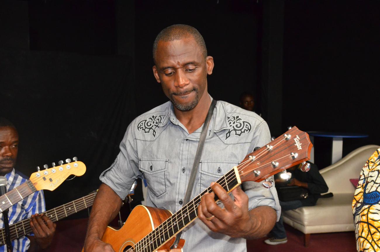 Man plays guitar in a jam session with other guitarists.