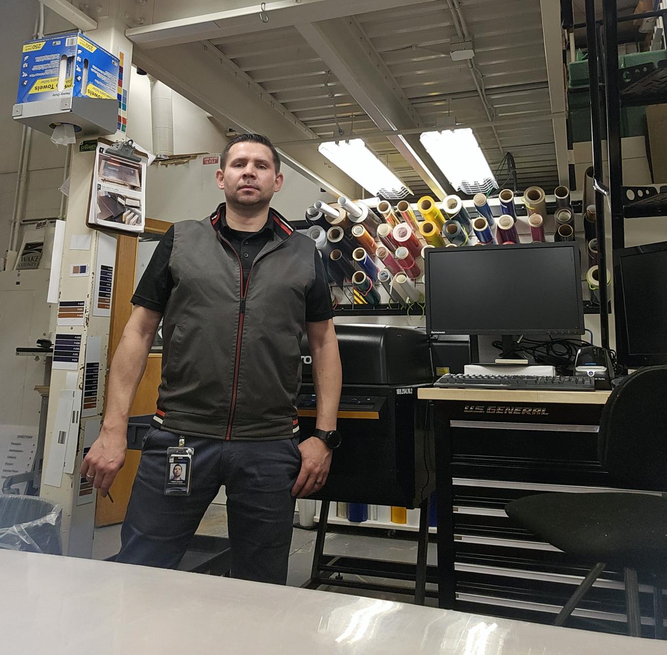 A man standing in a sign production workspace.