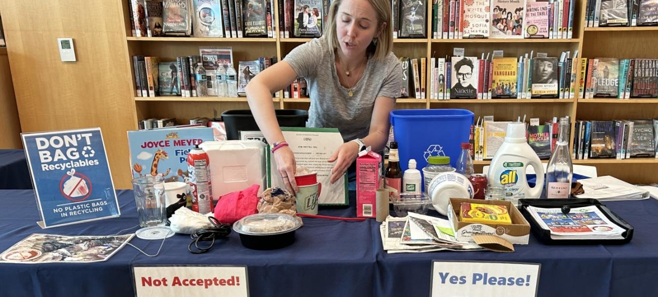 Woman standing at table with Solid Waste information and resources