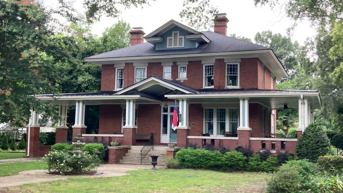Historic two-story brick house with a large covered porch and landscaped yard in Zebulon.