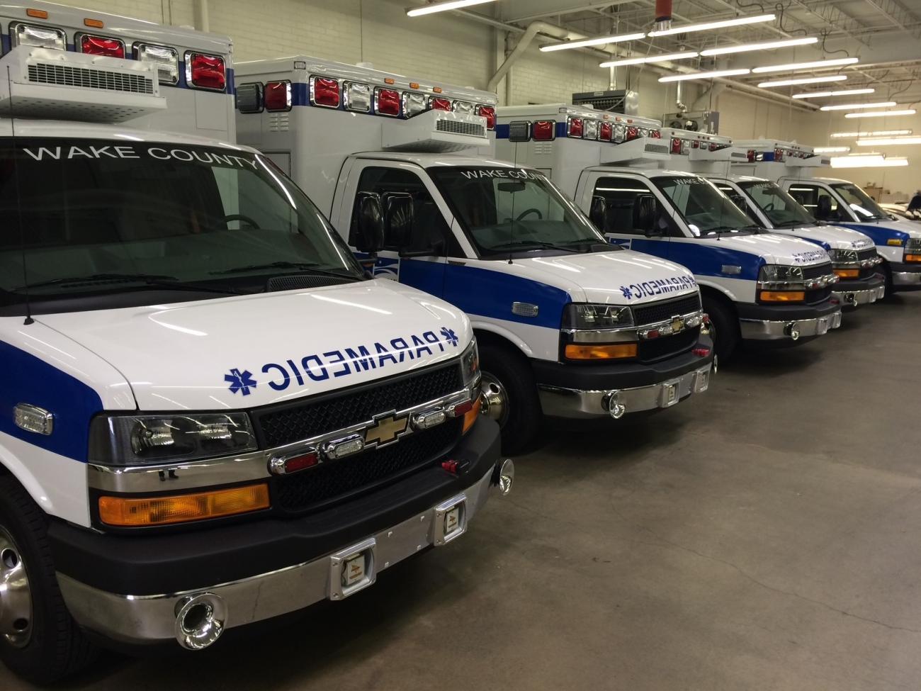 Row of Wake County ambulances parked inside a vehicle garage.