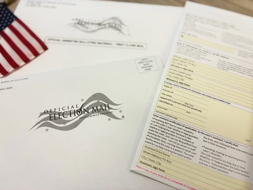 Close-up of an absentee ballot packet with an official election mail envelope and voting forms.