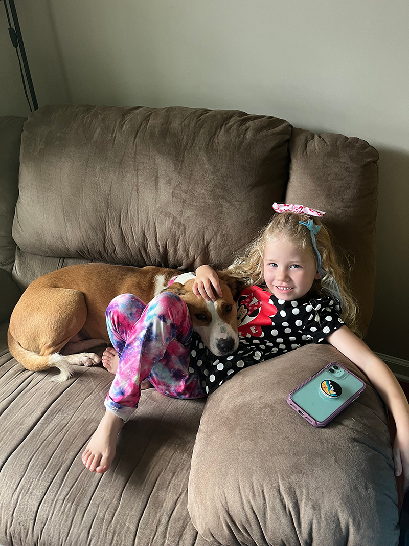 Mae cuddles with a child on a couch.