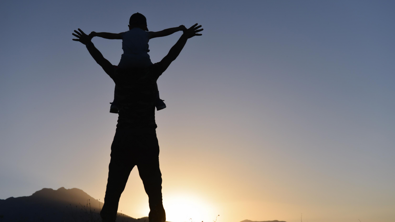 Silhouette of a father holding up his son on his shoulder