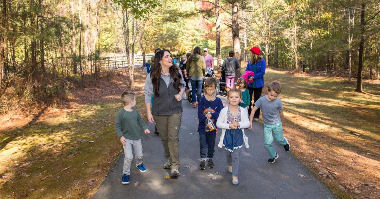 Programmer walks with children during a guided hike on the parks paved trails