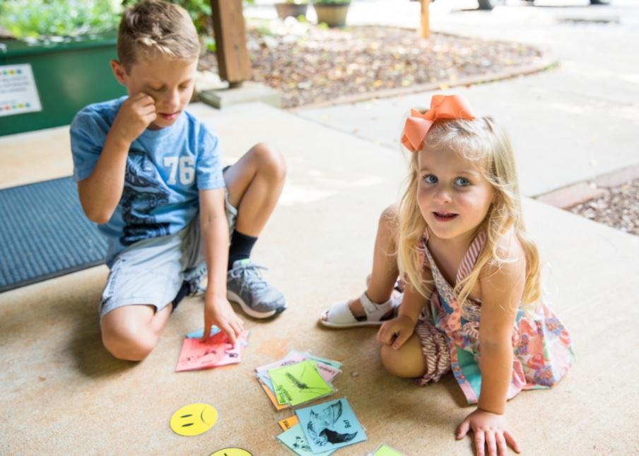 boy and girl look at nature activity while sitting on cement