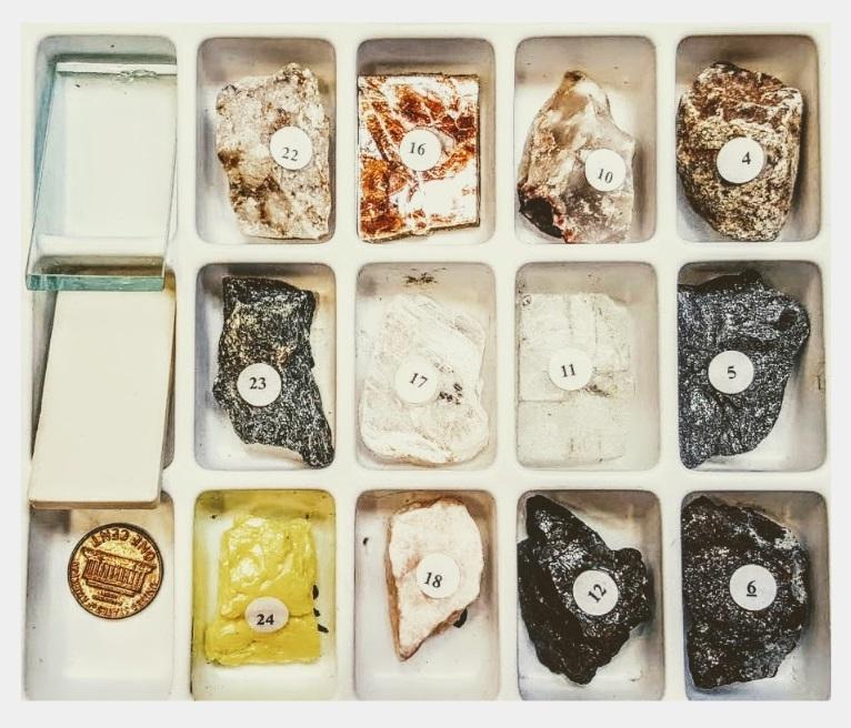 box filled with various types of rocks and rock testing equipment