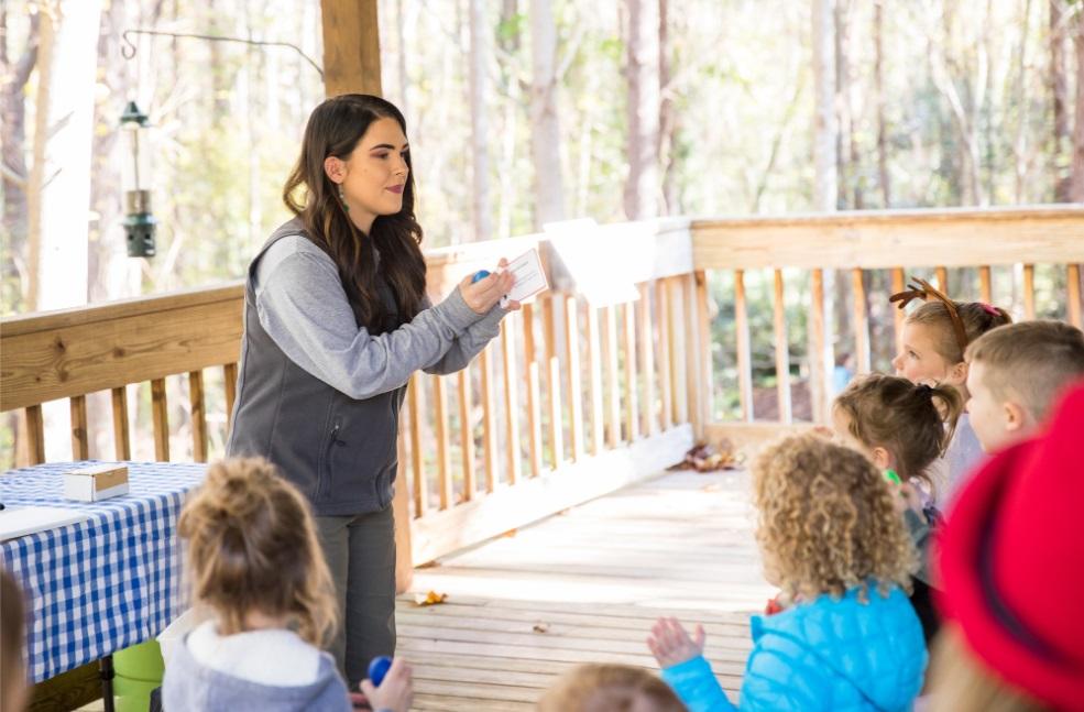 programmer explains a display with children under wooden shelter