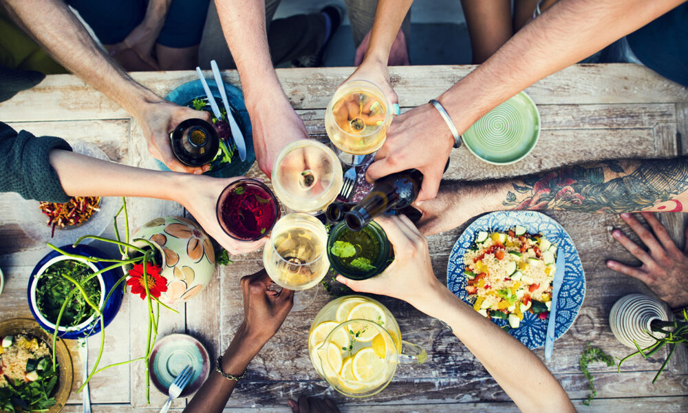 friends-toasting-over-vegan-food-over-picnic-table