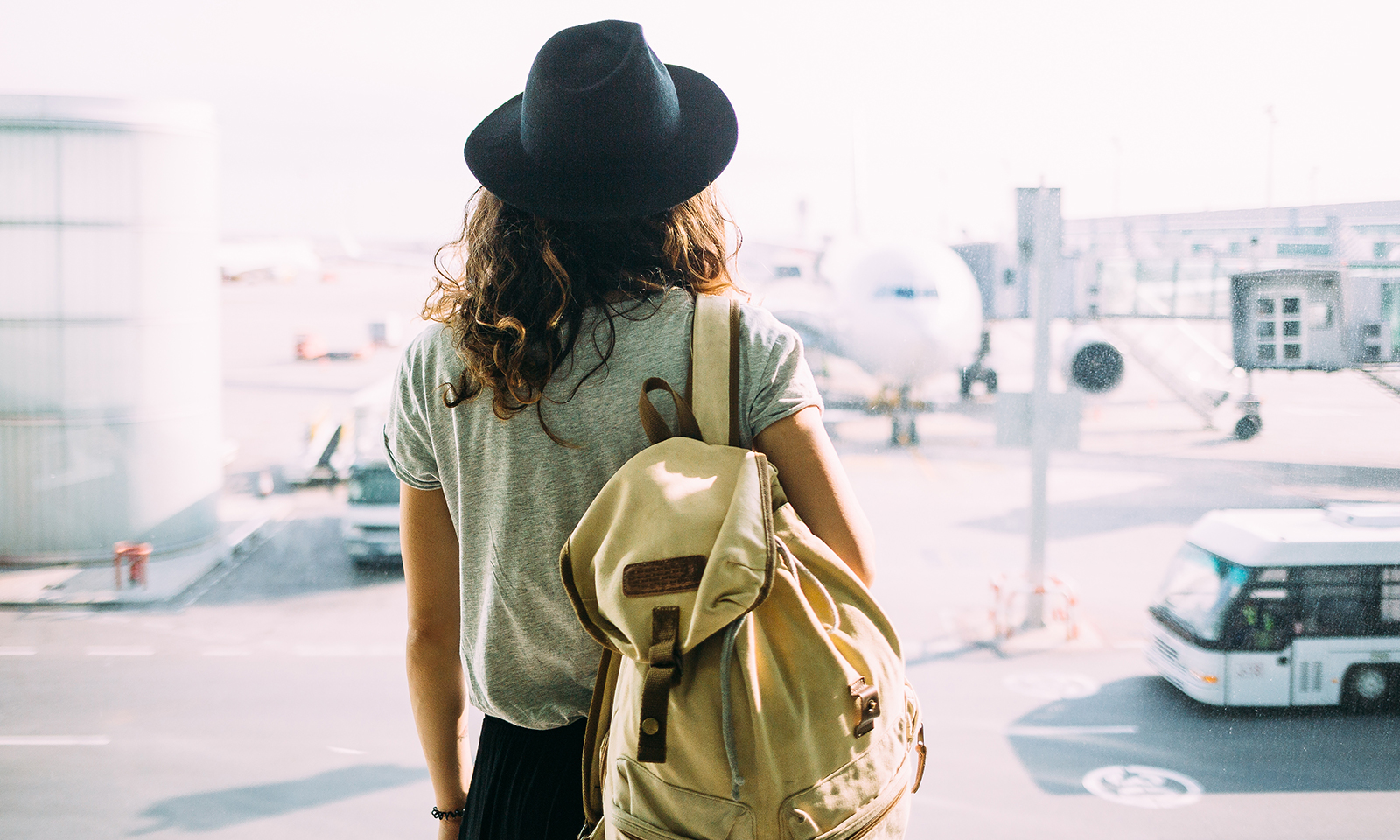 woman-staring-at-plane-with-packed-backpack