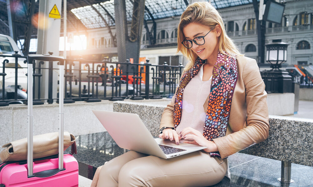 girl-on-computer-at-airport-with-luggage