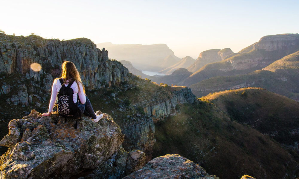 woman-sitting-over-ridge-in-nature-backpack