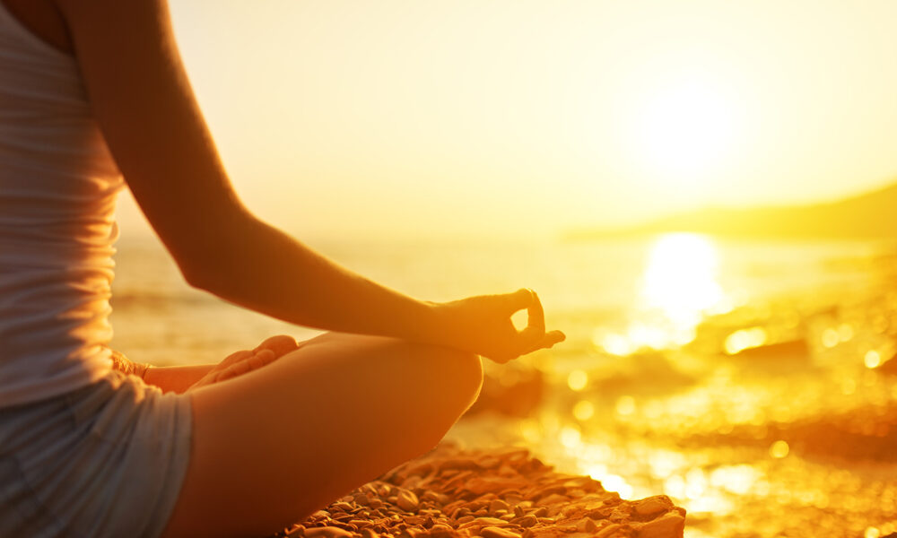 woman-sitting-on-beach-meditating