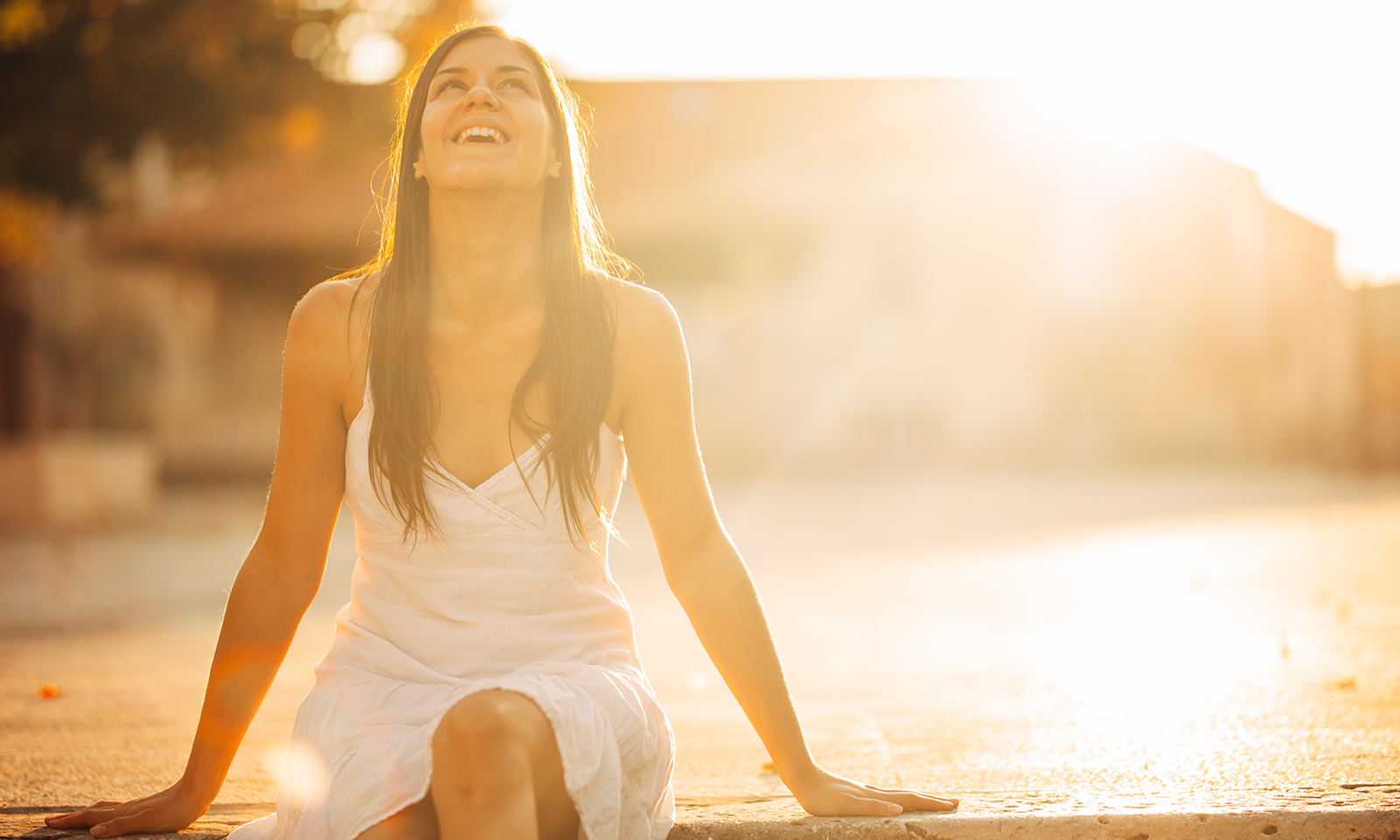 woman-sitting-on-pier-looking-up-in-the-sunlight