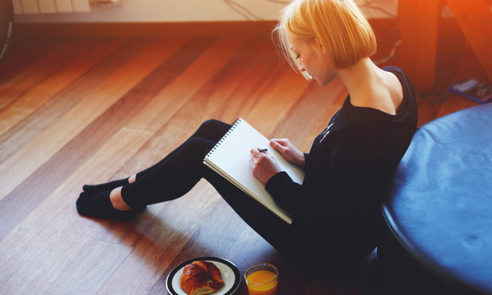 woman-sketching-in-a-pad-while-sitting-on-the-floor