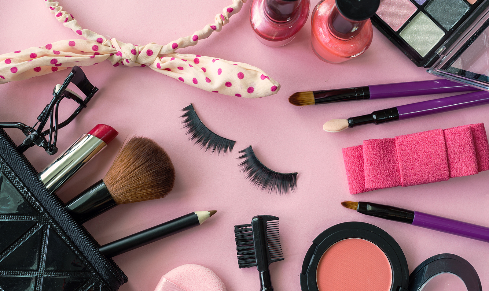 makeup-kit-makeup-items-laid-around-a-pink-background