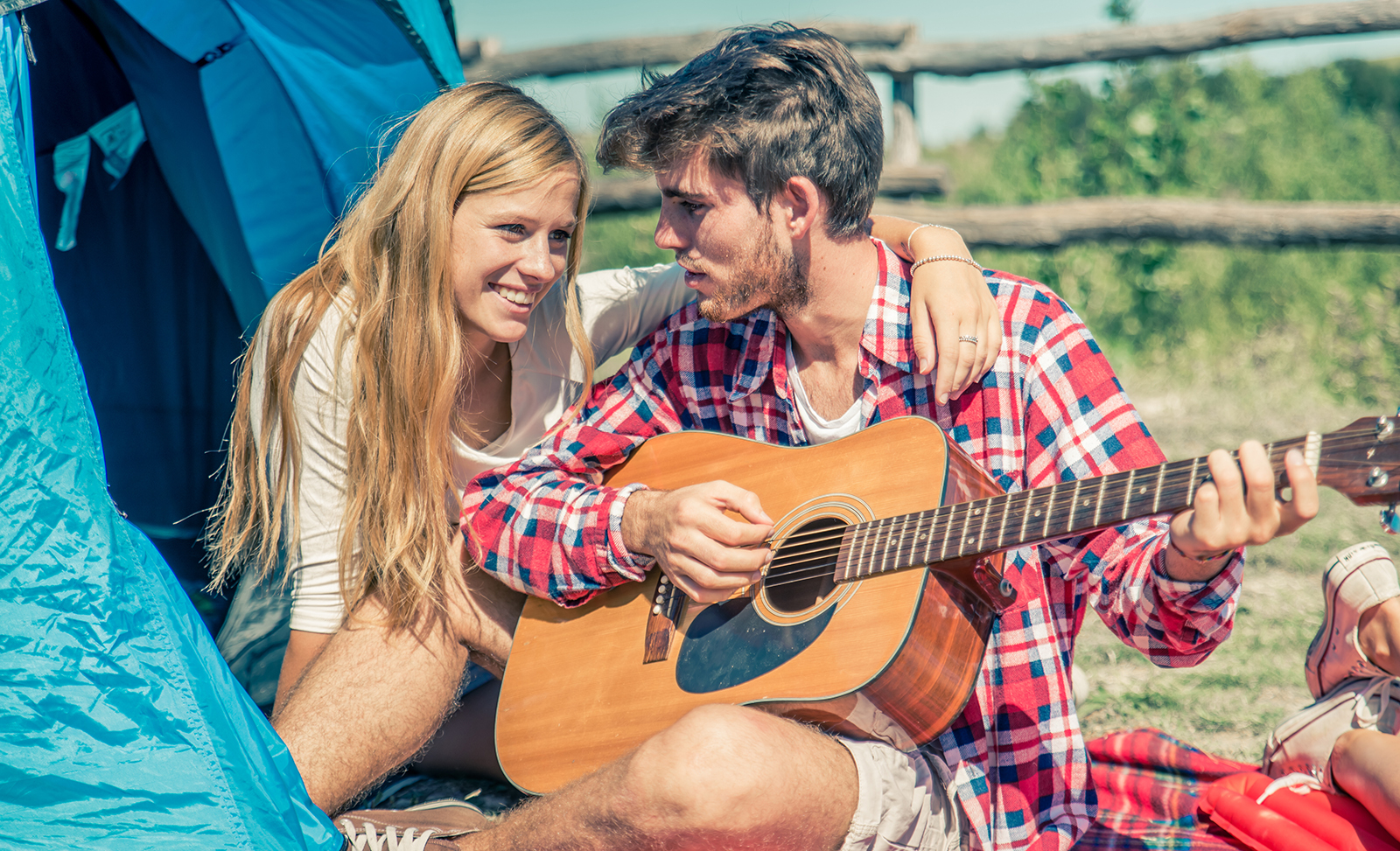 young-love-young-couple-camping-while-man-plays-guitar