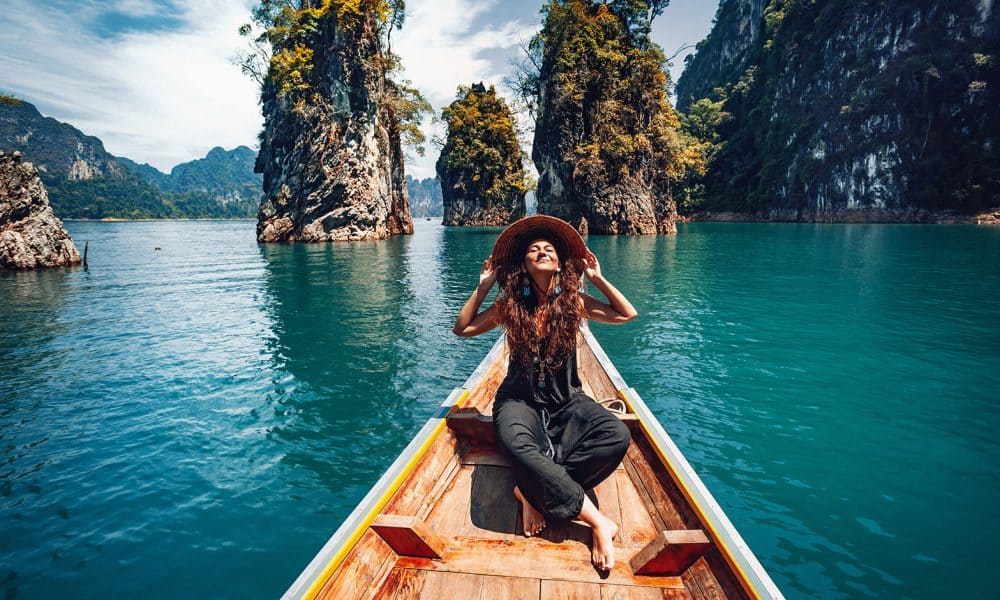 happy young woman tourist in asian hat on the boat at lake